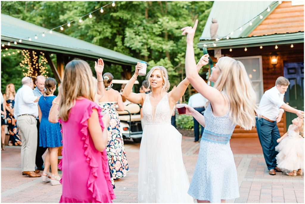 image of bride dancing with friends during wedding reception on patio under string lights