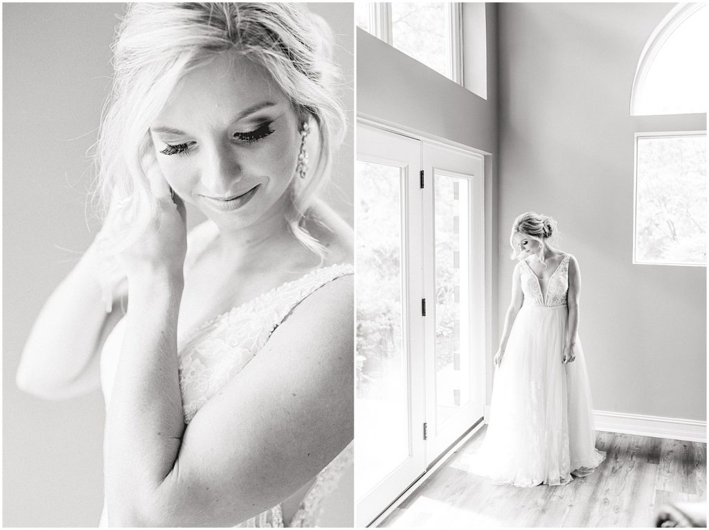 black and white image of bride putting earrings on and standing next to window