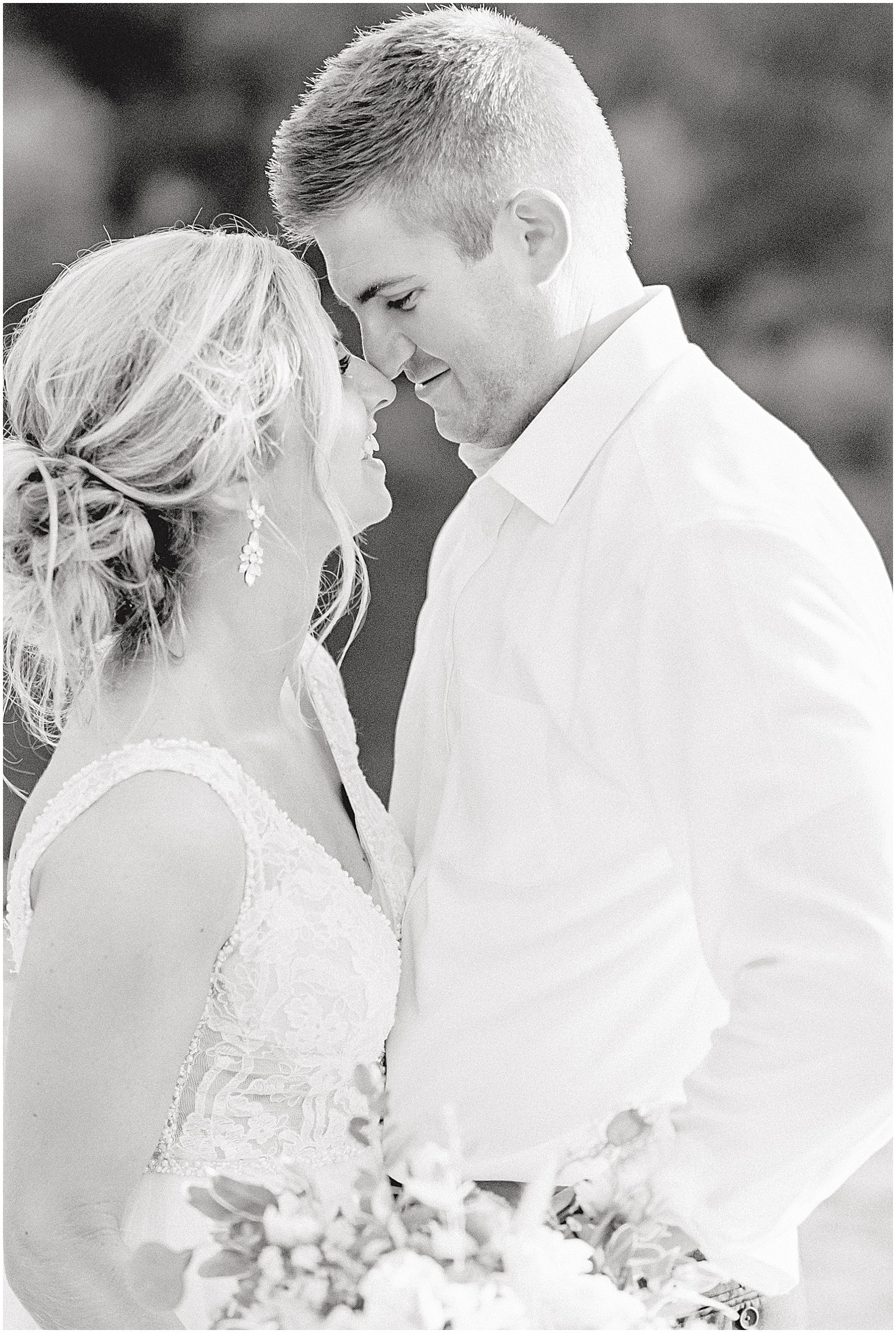 black and white image of bride and groom smiling at each other during sunset portraits on wedding day in Hermann, mo