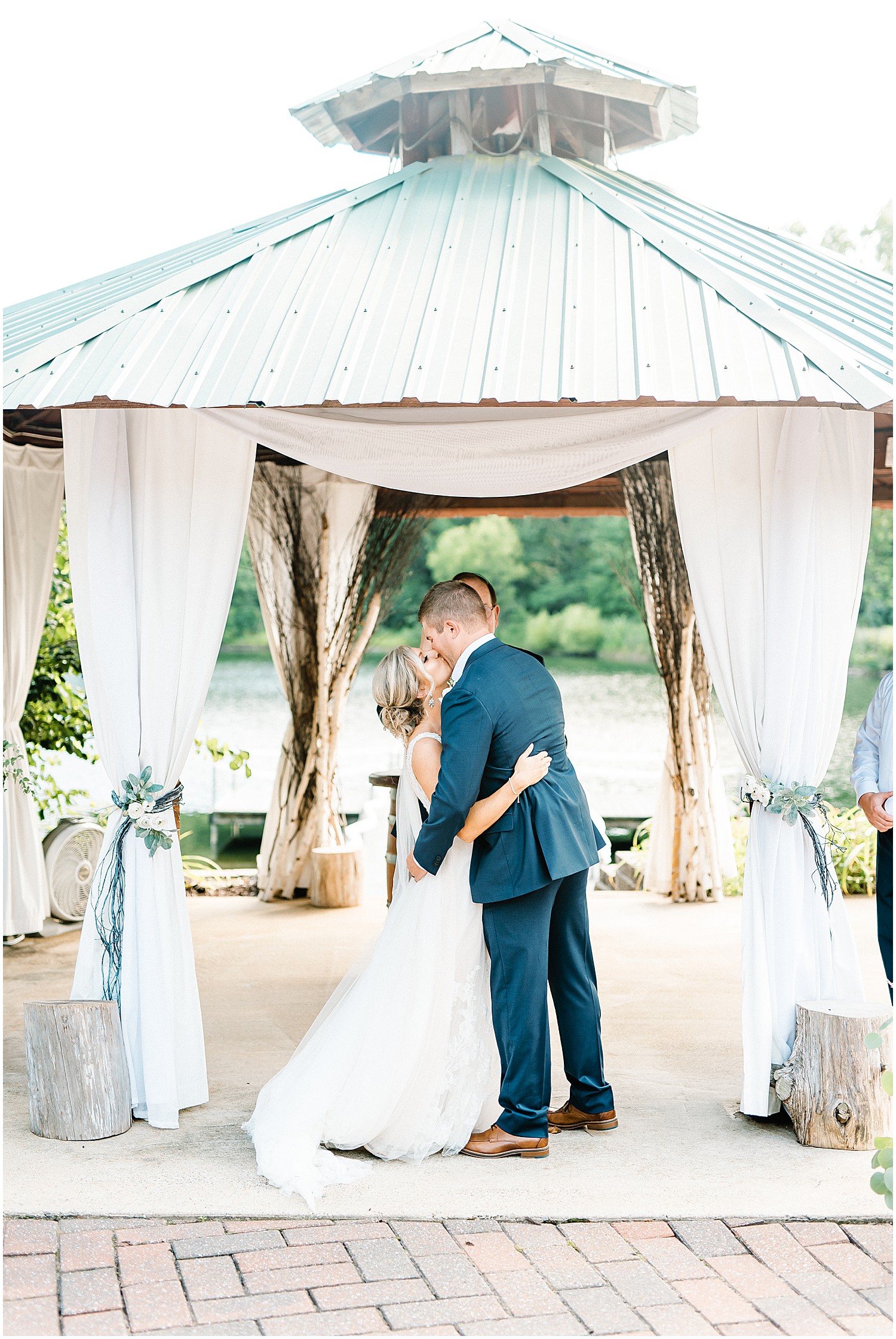 bride and groom first kiss near the lake at little piney lodge wedding ceremony