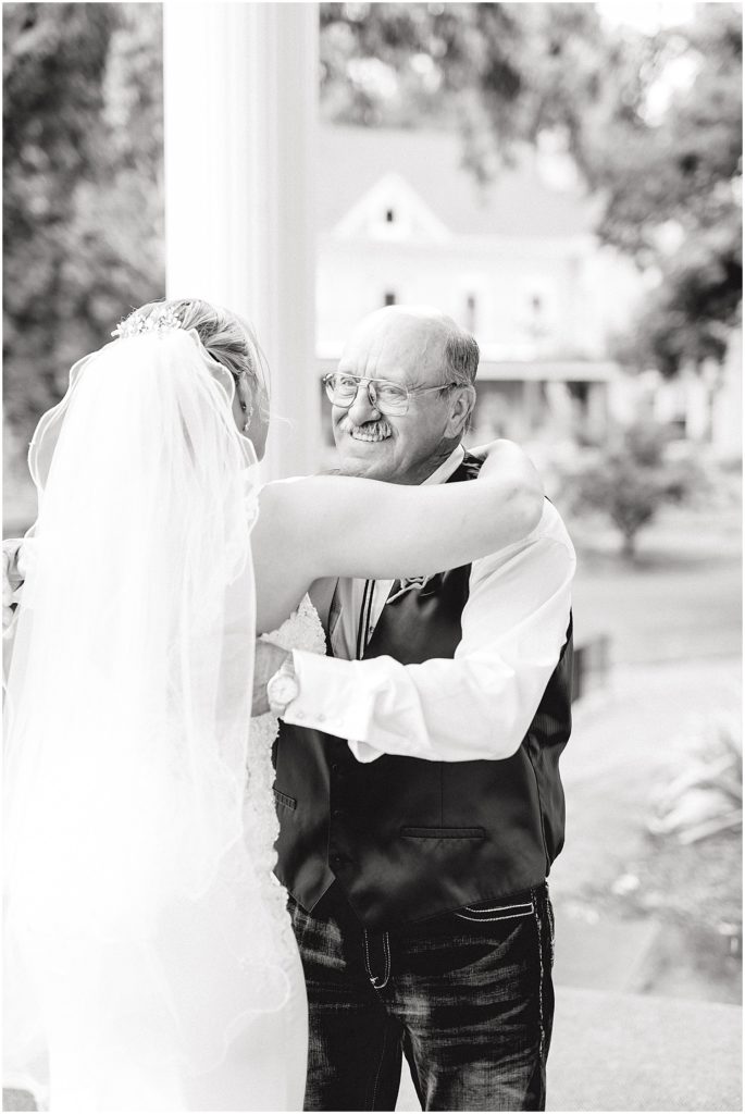 black and white image of father of the bride hugging daughter on wedding day after first look