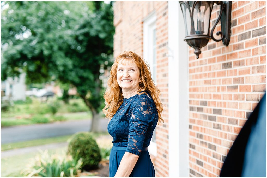 mother of the groom smiling at groom  after first look outside of church on wedding day