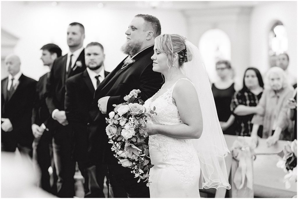 black and white image of bride and groom standing at altar on wedding day