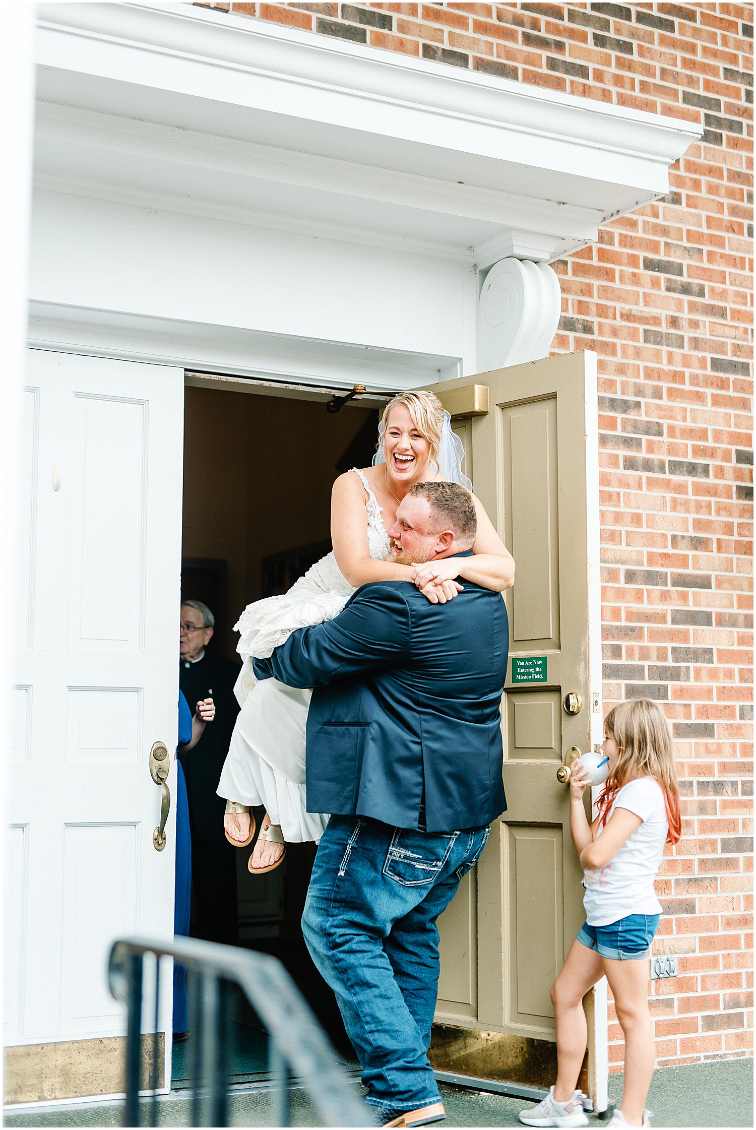 groom carrying bride out of church after wedding ceremony