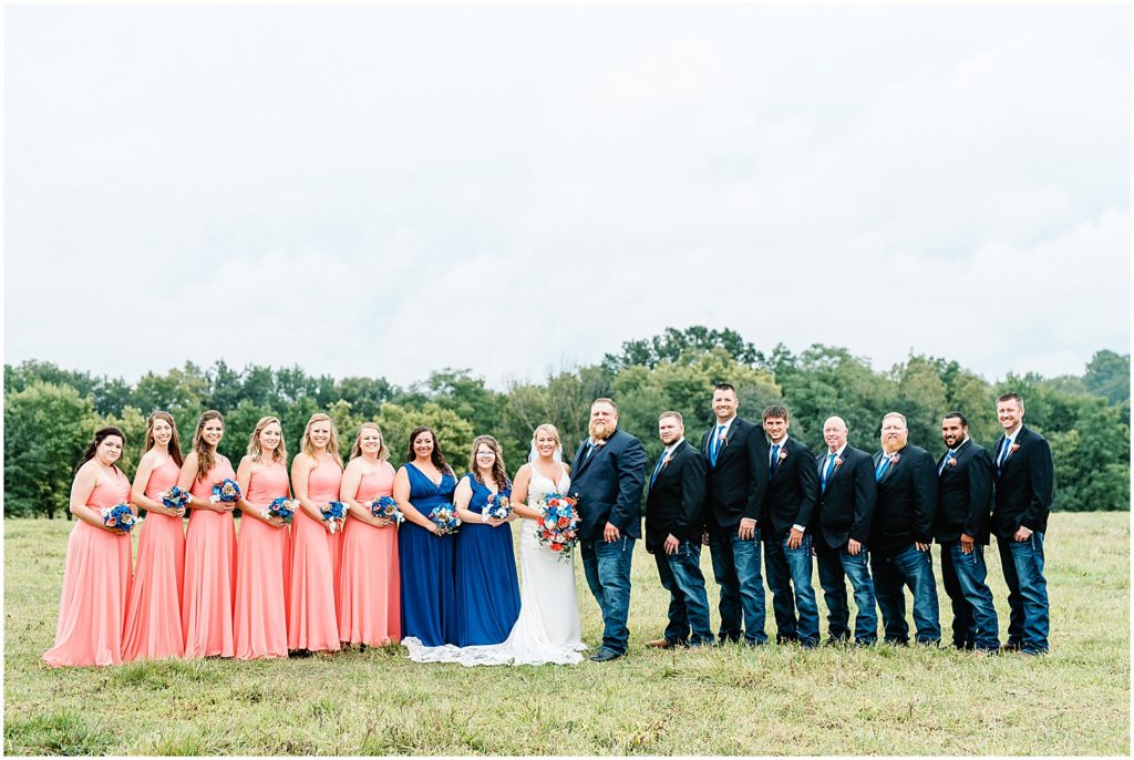 wedding party standing in field wearing pink and navy with bride and groom