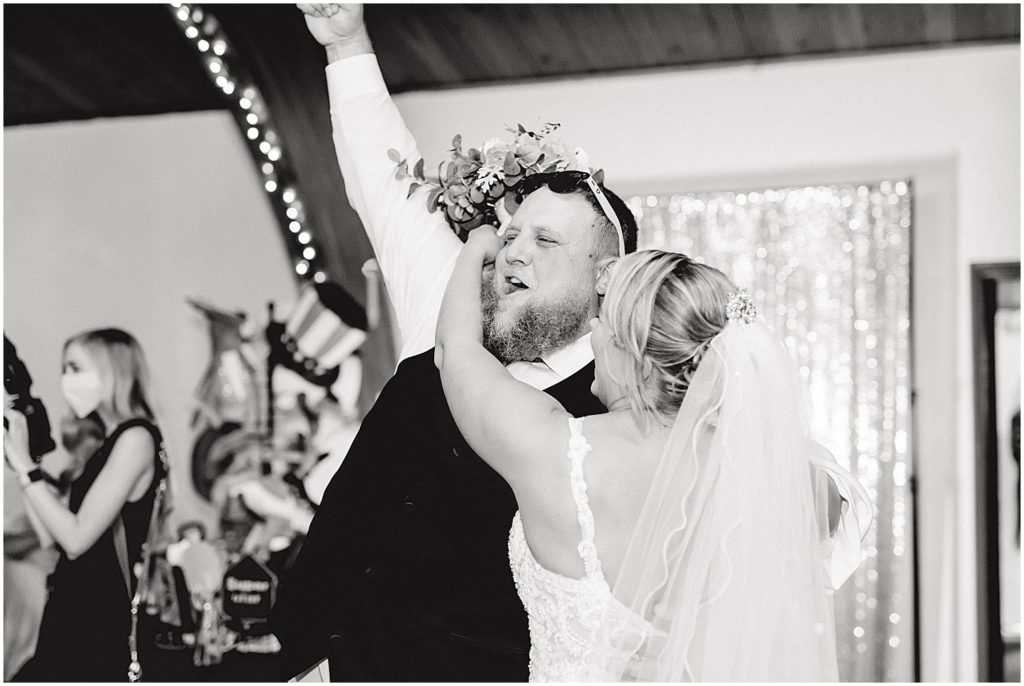 black and white image of bride and groom entering wedding reception and cheering