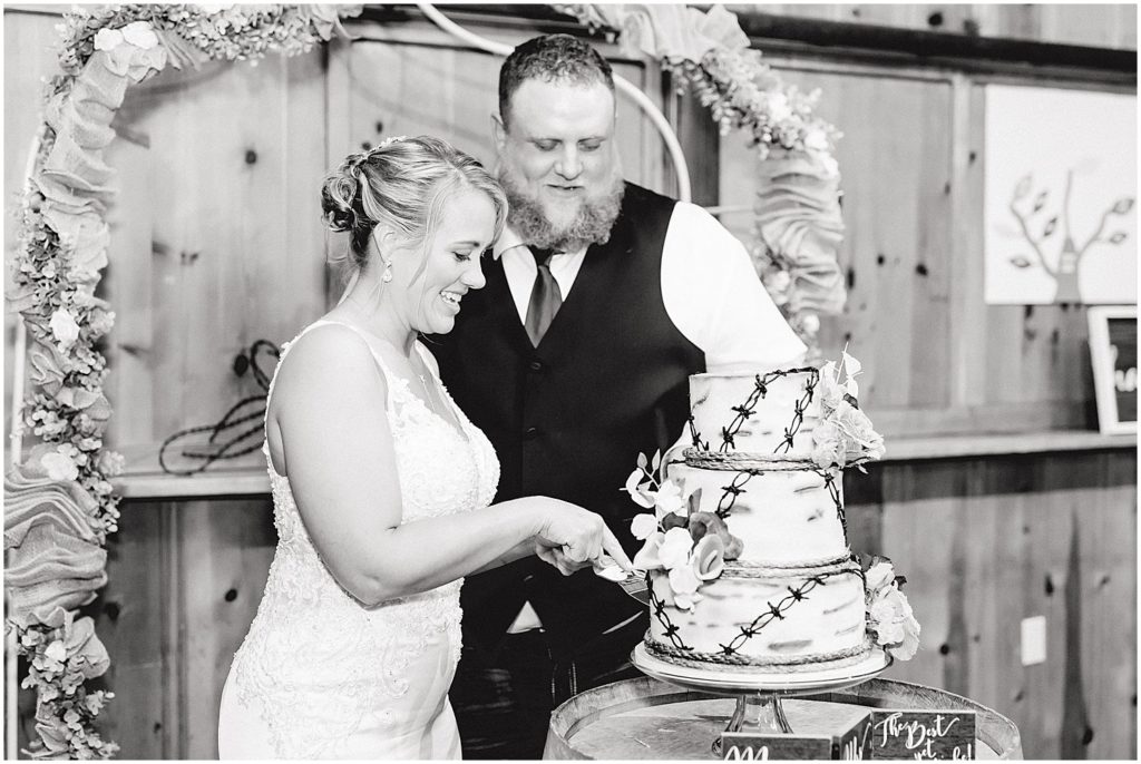 black and white image of bride and groom cutting cake during wedding reception