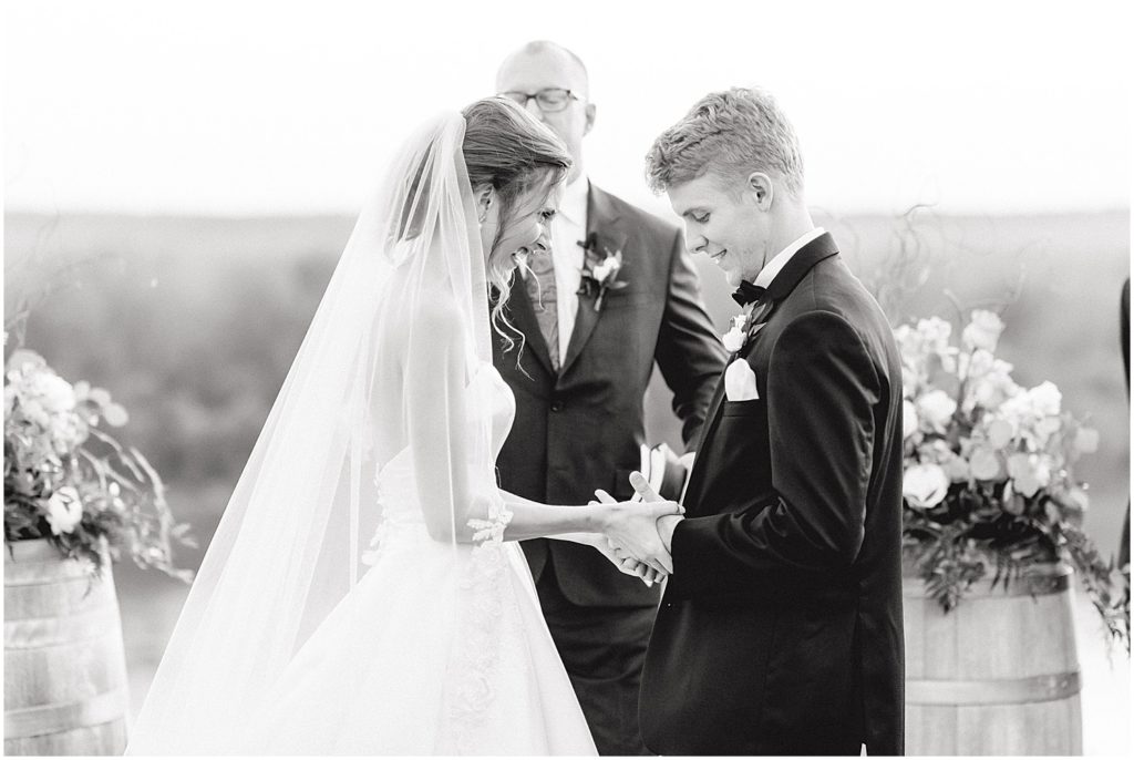 black and white image of bride and groom exchanging rings during wedding ceremony