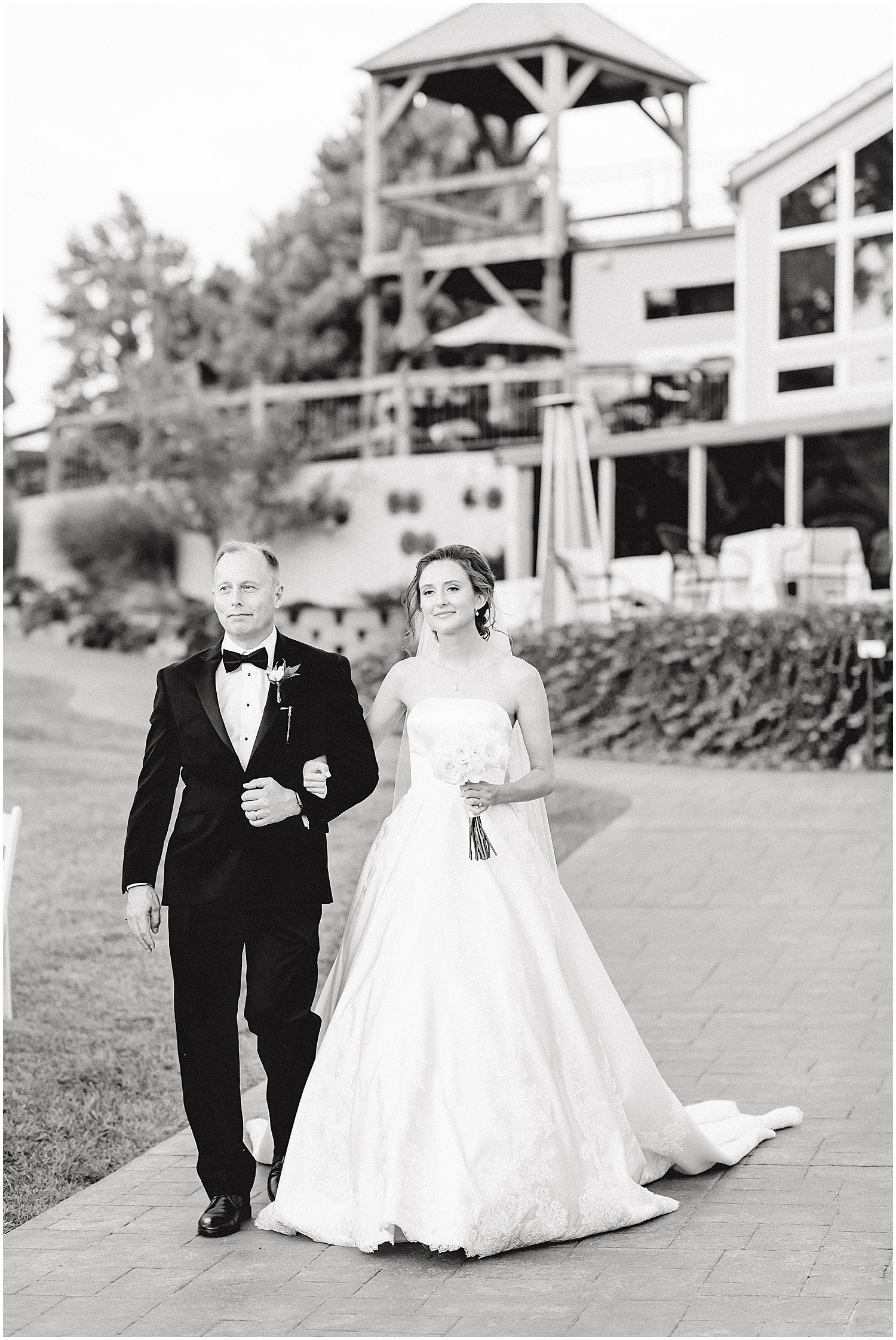 black and white image of bride and father walking down the aisle outside of les bourgeois winery