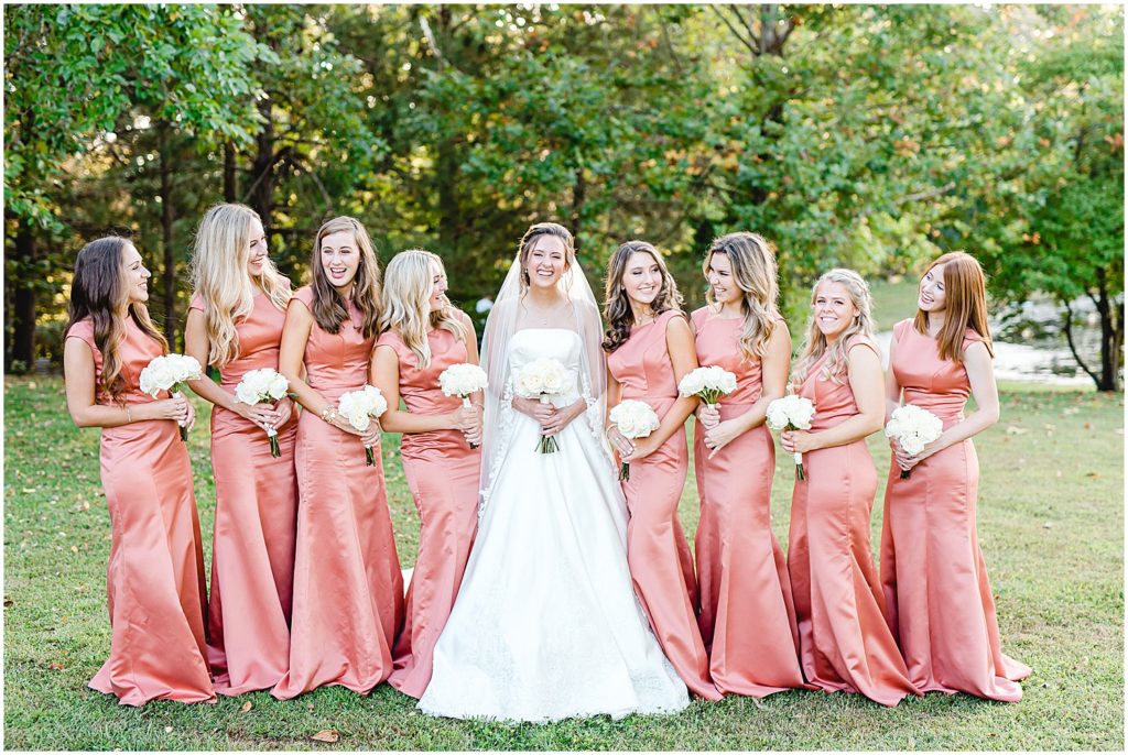bride and bridesmaids laugh during portraits on wedding day