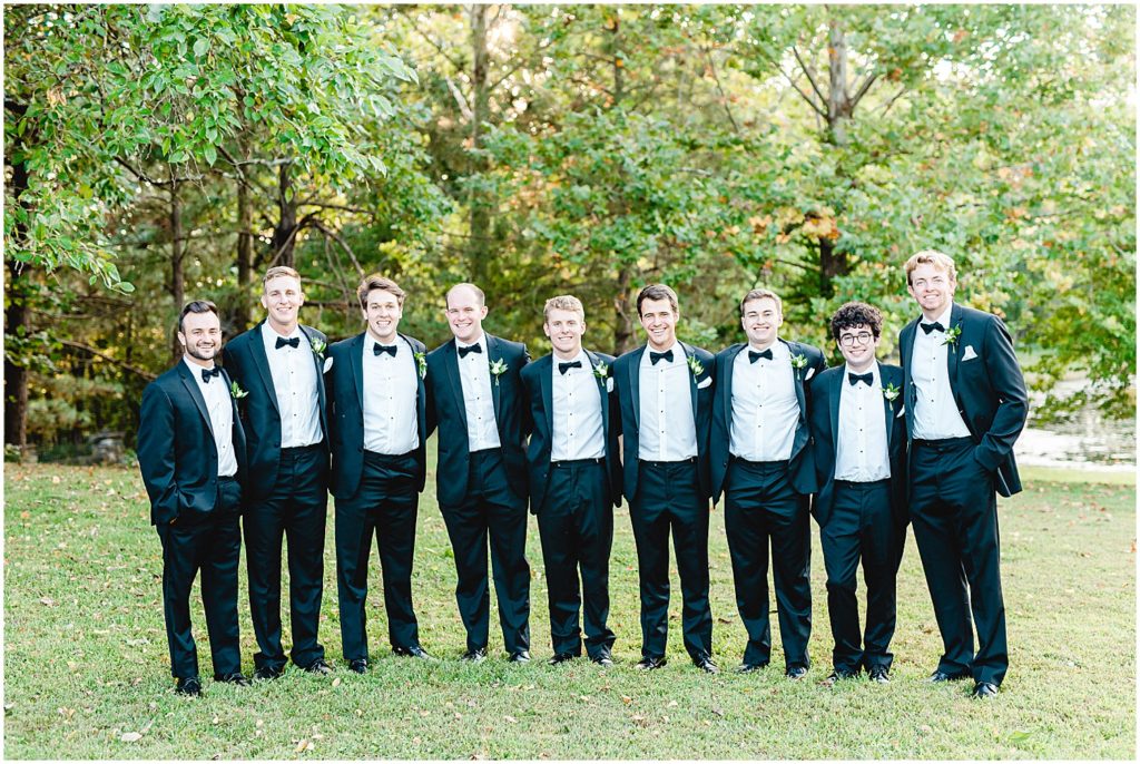 groom and groomsmen wearing black tuxes during portraits on wedding day