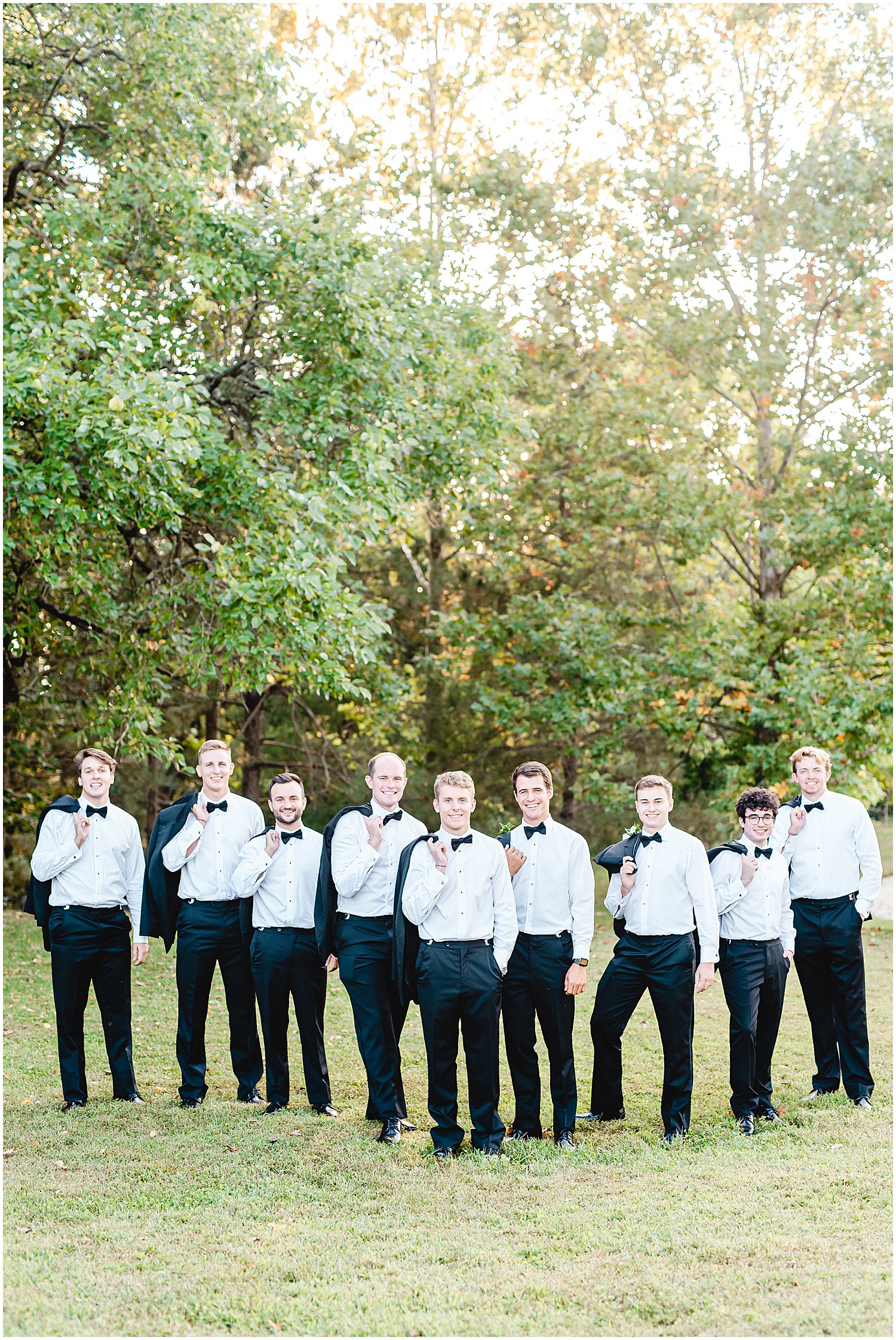 groom and groomsmen pose for portraits on wedding day with jackets over shoulders