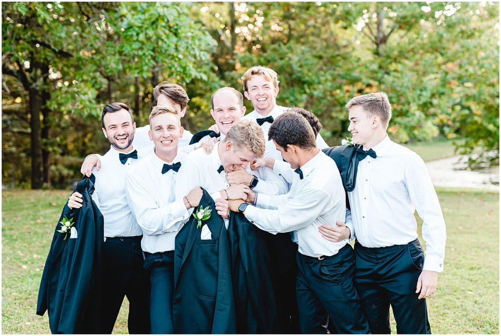 groomsmen tickle groom during portraits on wedding day