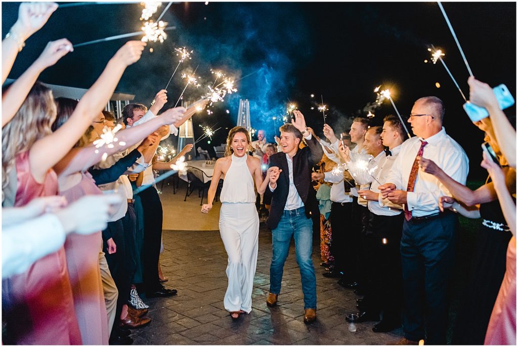 bride and groom walking through tunnel of sparklers after wedding reception