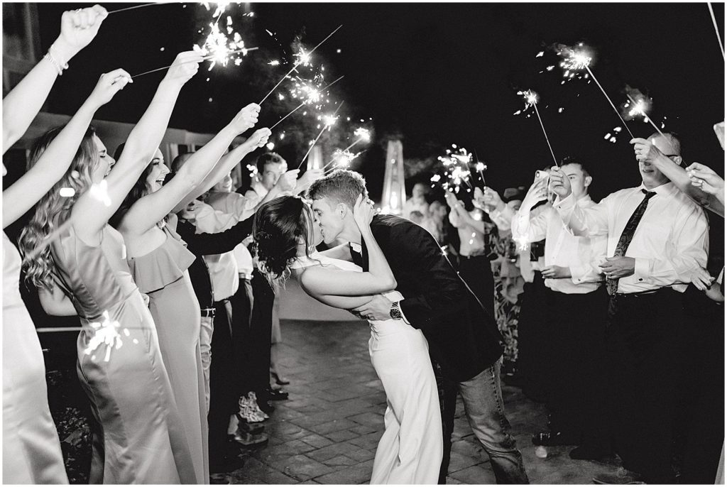 black and white image of bride and groom kissing under sparklers during les bourgeois winery wedding day