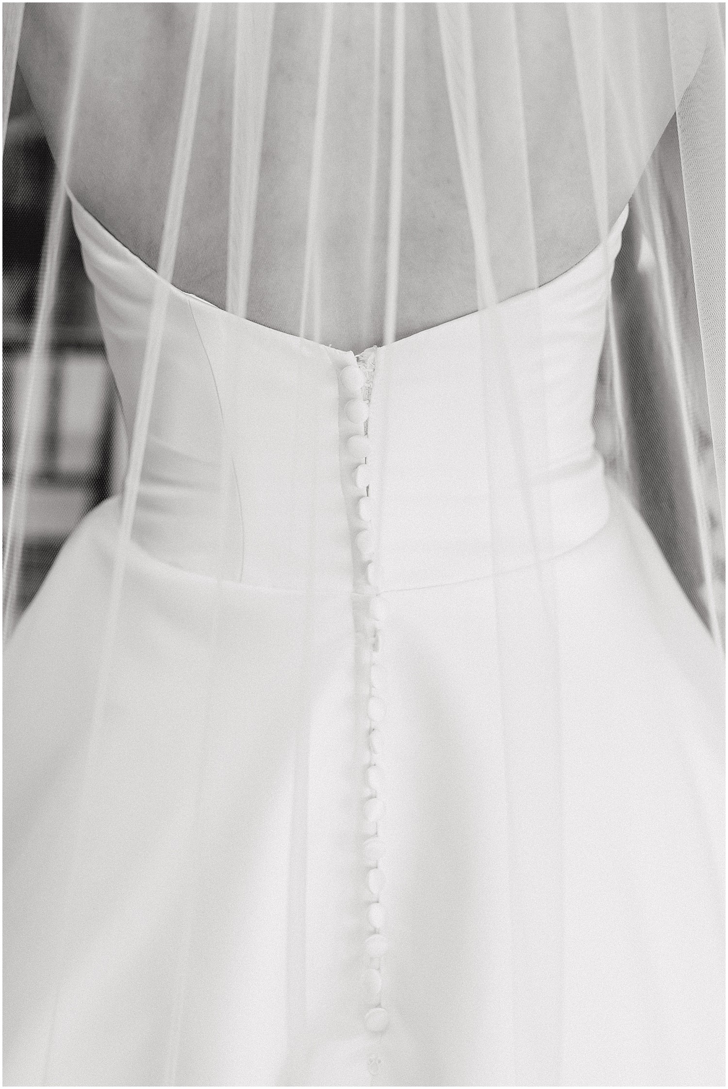 black and white image of back of bridal gown with veil flowing down