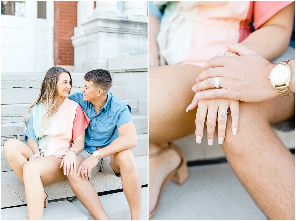 couple sits on stairs holding hands showing engagement ring