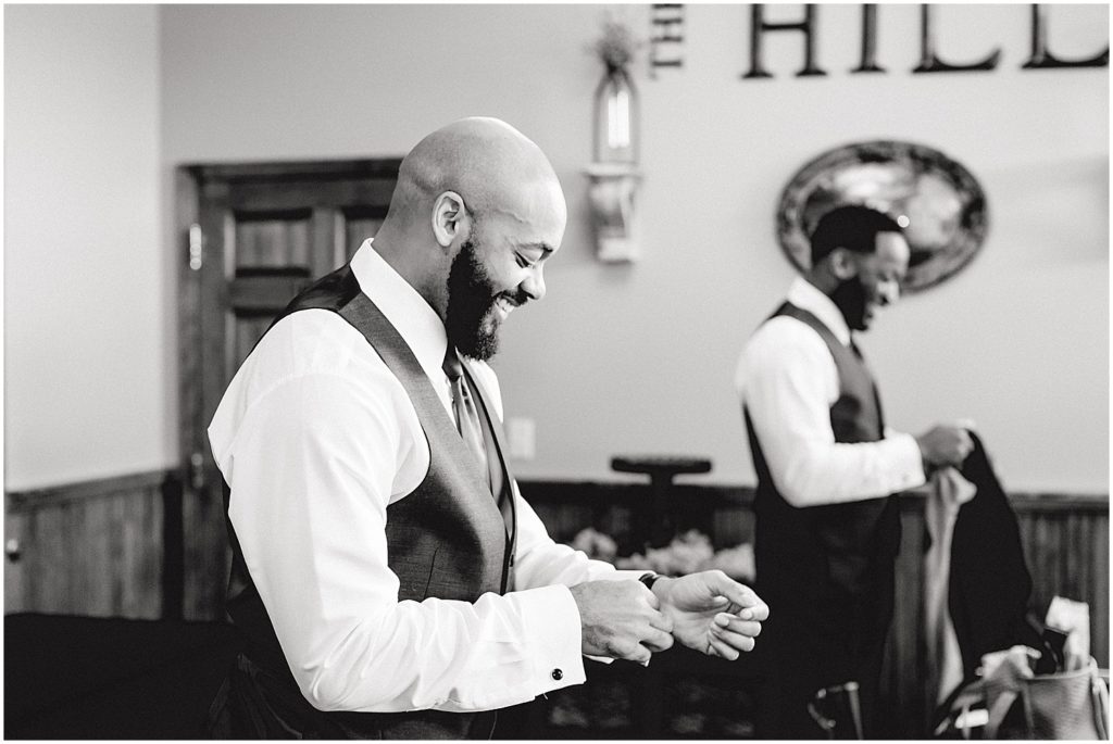 black and white image of groom in getting ready room adjusting sleeves at Canterbury hill winery