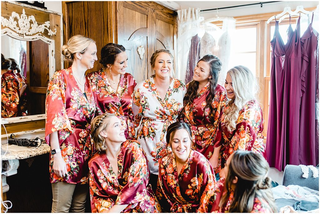 bride and bridesmaids laughing in maroon floral wedding party robes