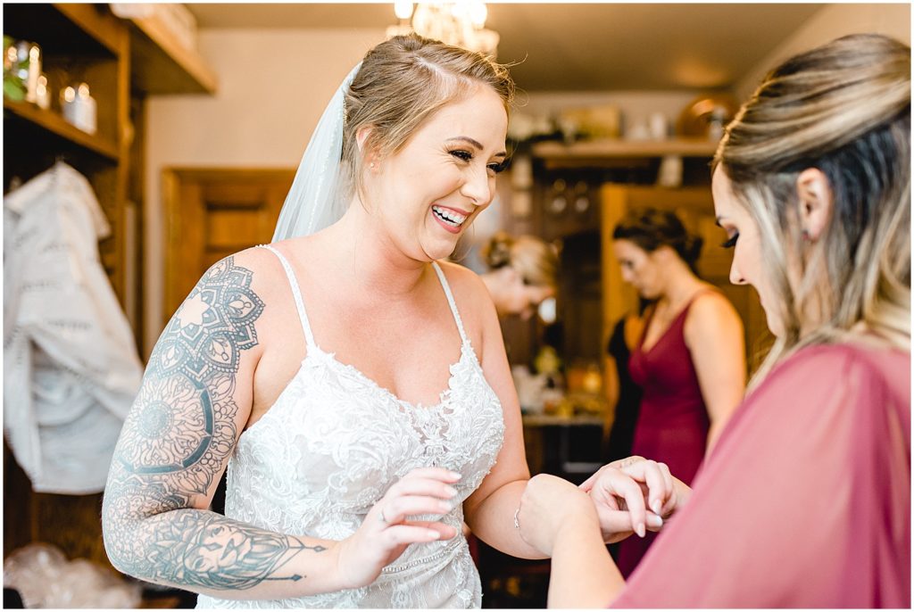 bride smiling as she has a bracelet put on her while getting ready at Canterbury hill winery.