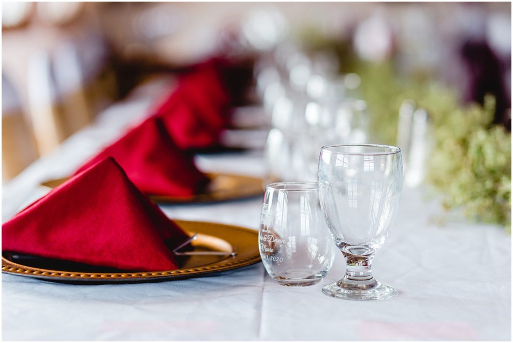 reception table details with maroon napkins and custom glasses at wedding reception