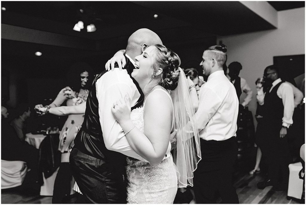 black and white image of bride and groom laughing while they dance during wedding reception at Canterbury hill winery
