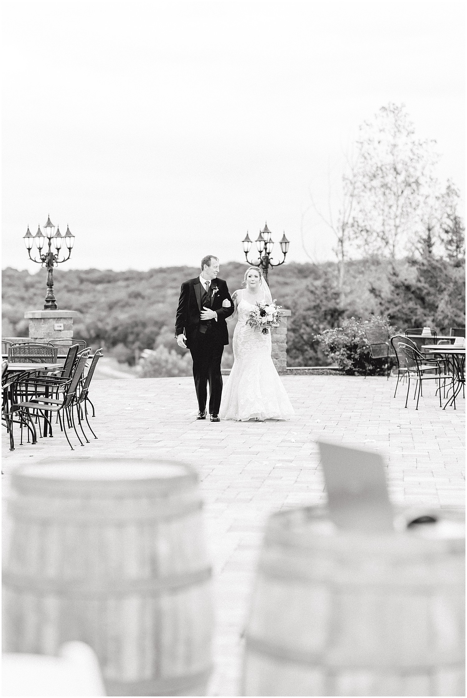 black and white image of bride and father walking towards wedding ceremony on patio at canterbury hill winery