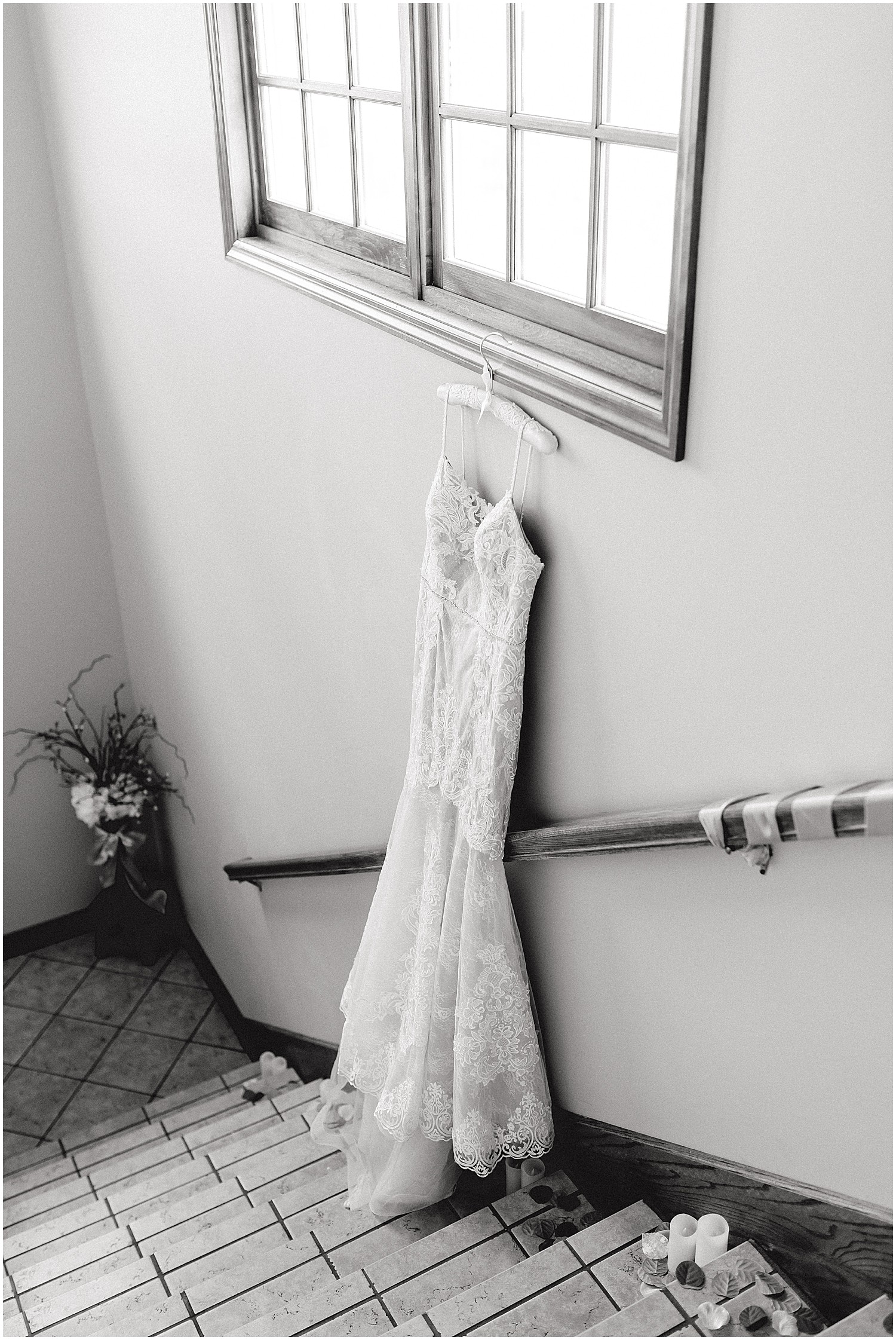 black and white image of bridal gown hanging on wall on staircase