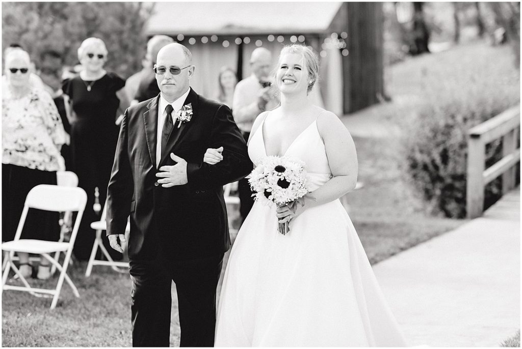 black and white image of bride walking down the aisle with her dad at kempker's back 40