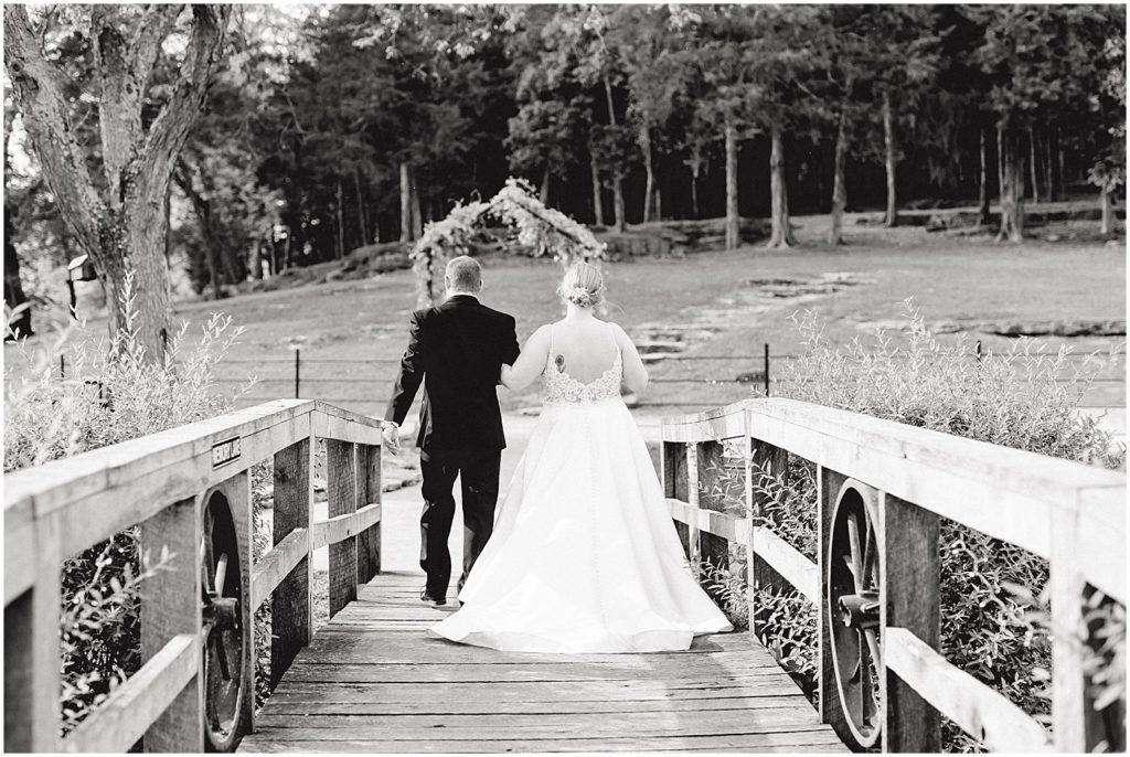 black and white image of bride and groom walking away over the bridge after their wedding ceremony