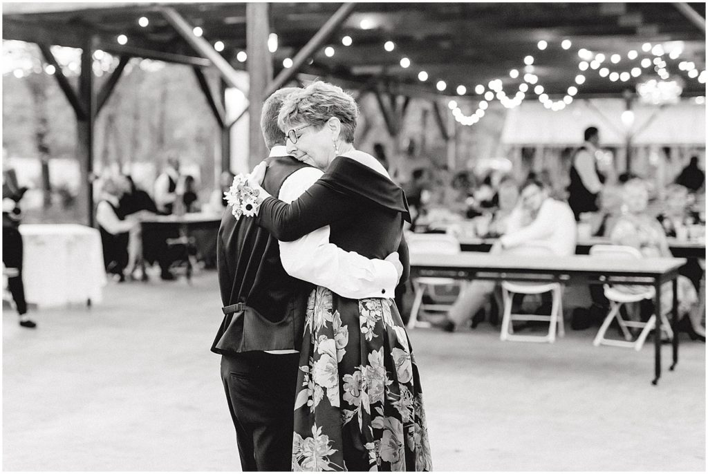 black and white image of groom and mom hugging after first dance on wedding day