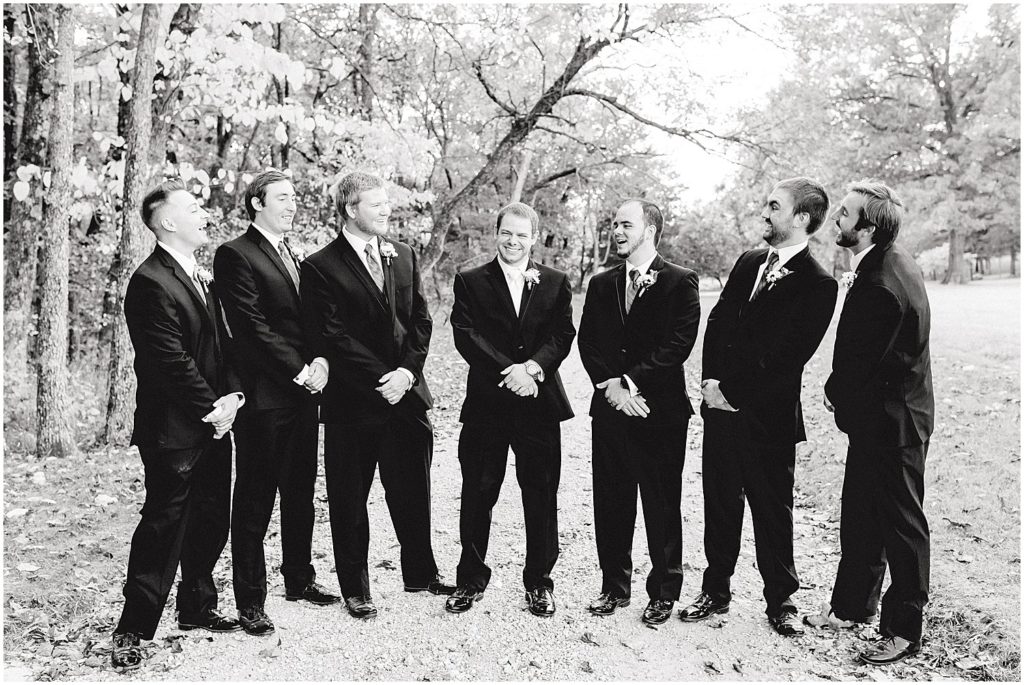 black and white image of groom and groomsmen laughing during photos