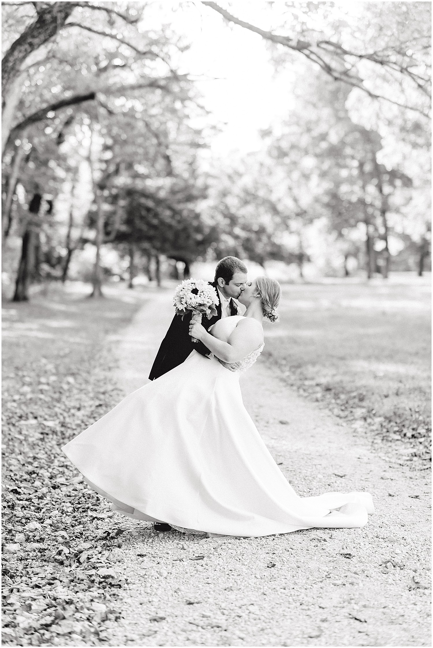 black and white image of bride and groom kissing under trees on kempker's back 40 wedding day
