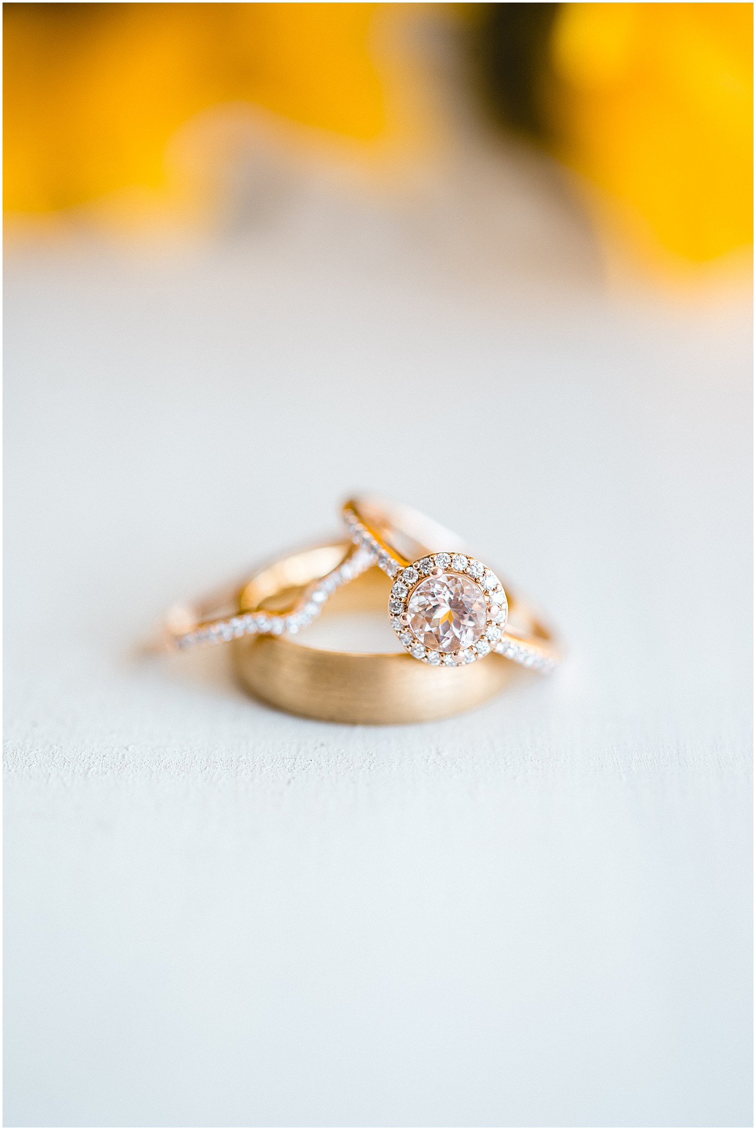 set of three gold and diamond wedding rings on white background in front of sunflower
