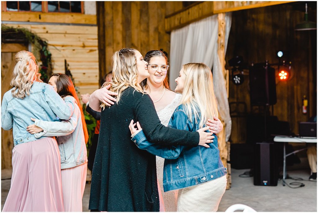 bride dances with friends during wedding reception in barn