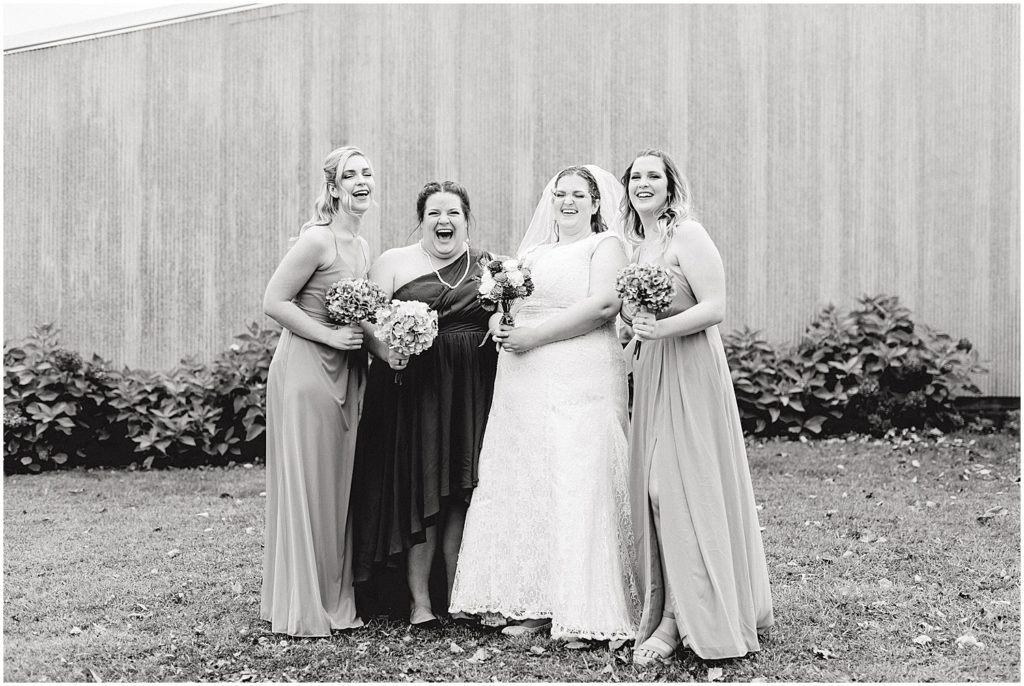 black and white image of bride and bridesmaids laughing during wedding party portraits
