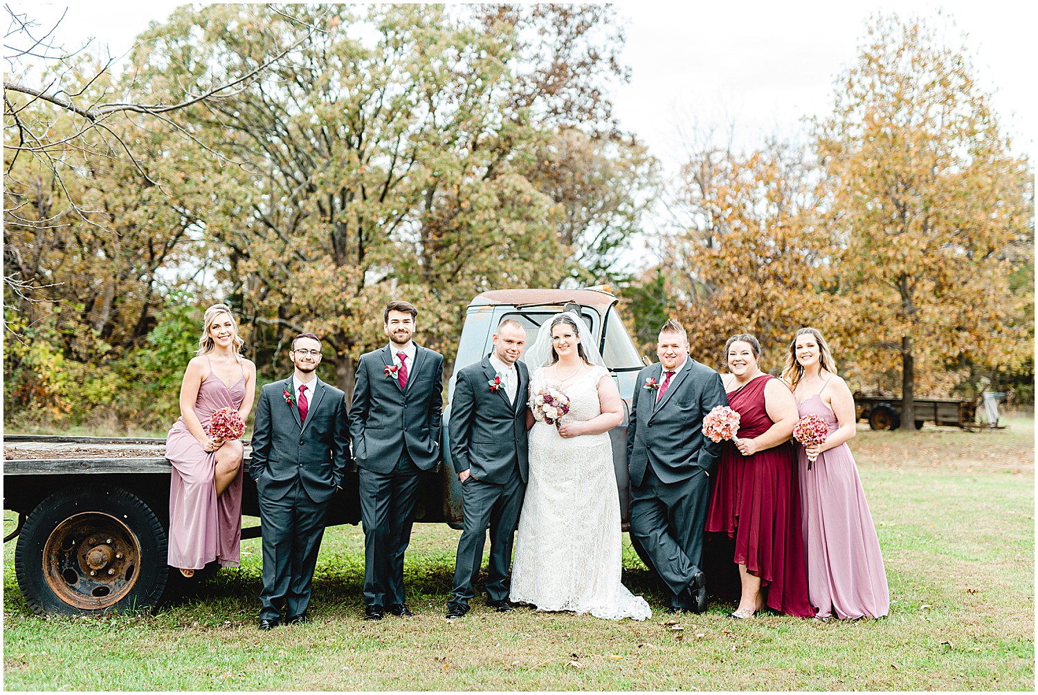 wedding party stands in front of old green farm truck