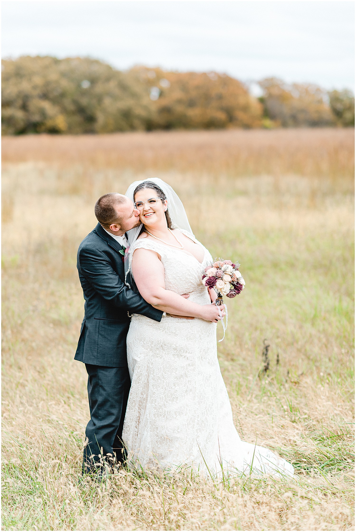 bride and groom kissing in a field in wedding day attire at wildflower wedding venue
