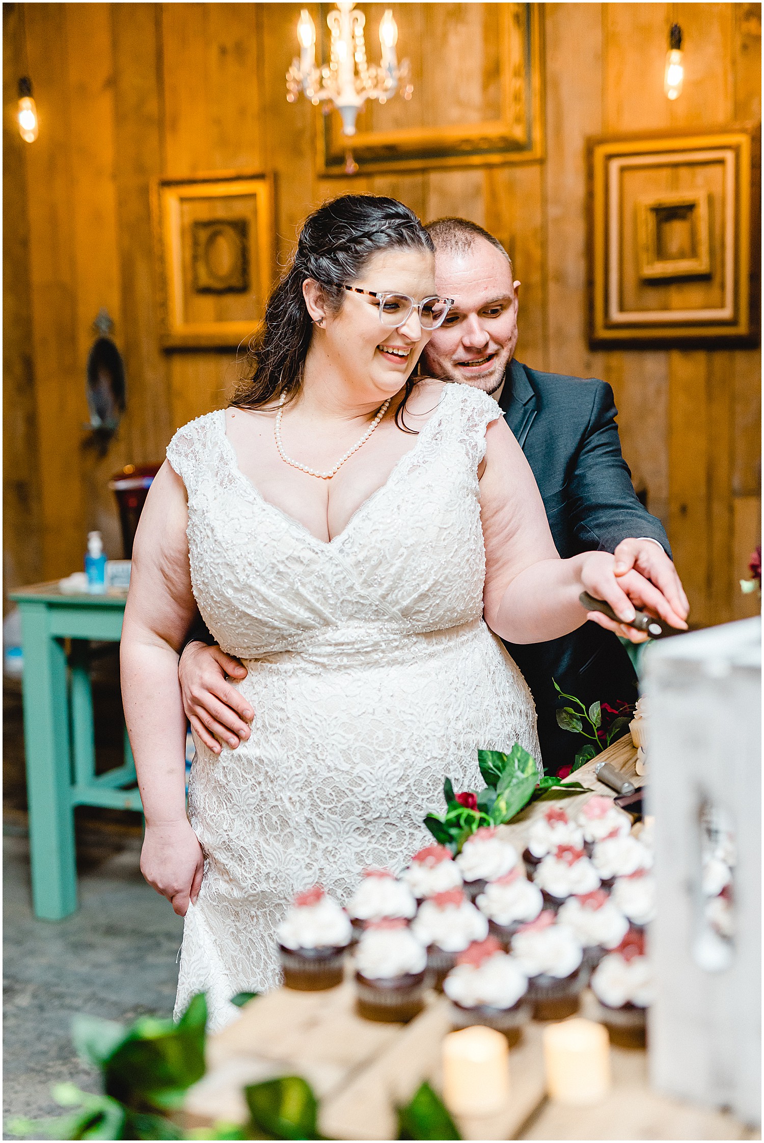 bride and groom cut the cake during wedding reception in barn