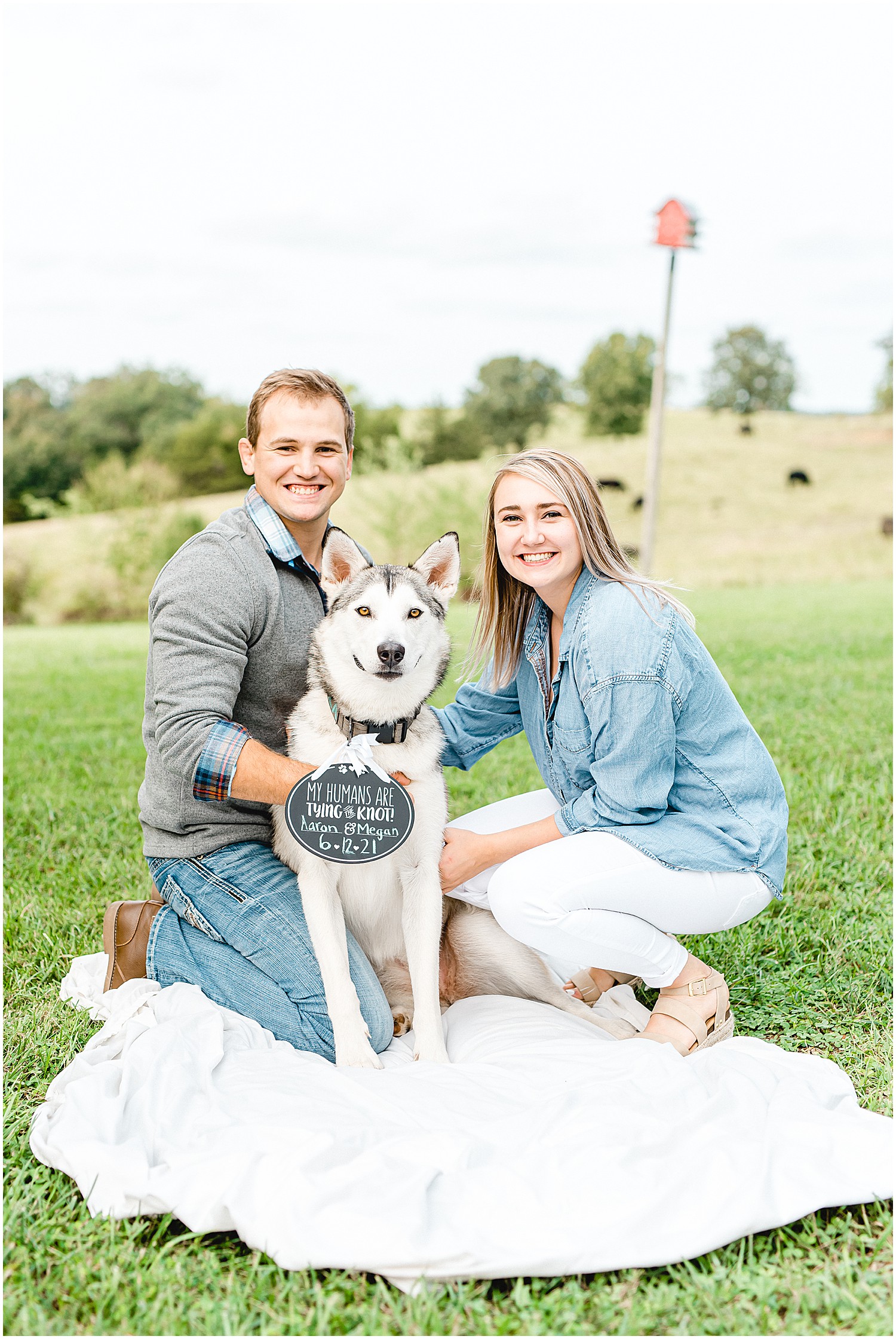 engaged couple poses with husky dog with sign around neck