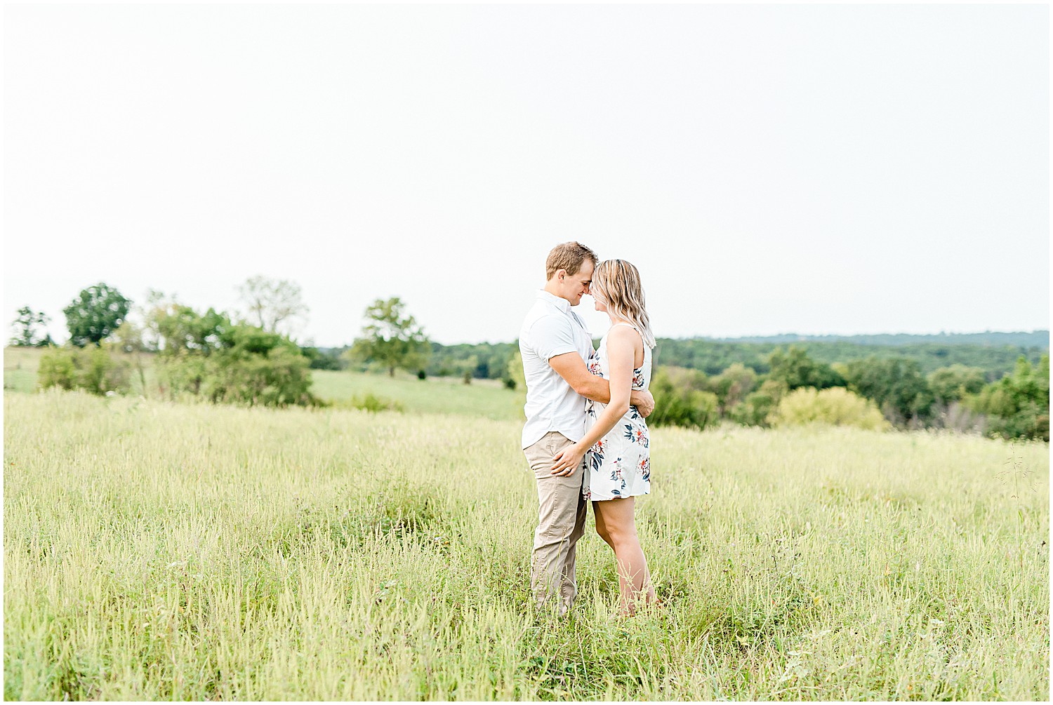 engaged couple hugs in a grassy field on family farm engagement session in missouri