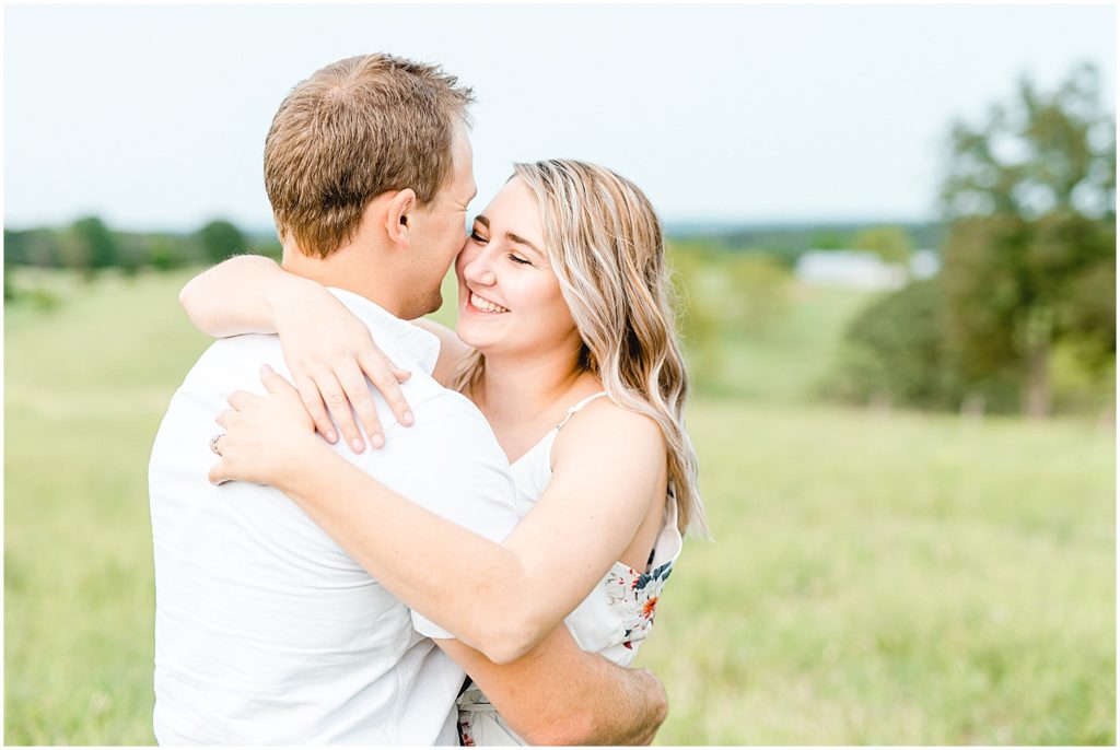 girl and boy hug and smile during engagement session on farm