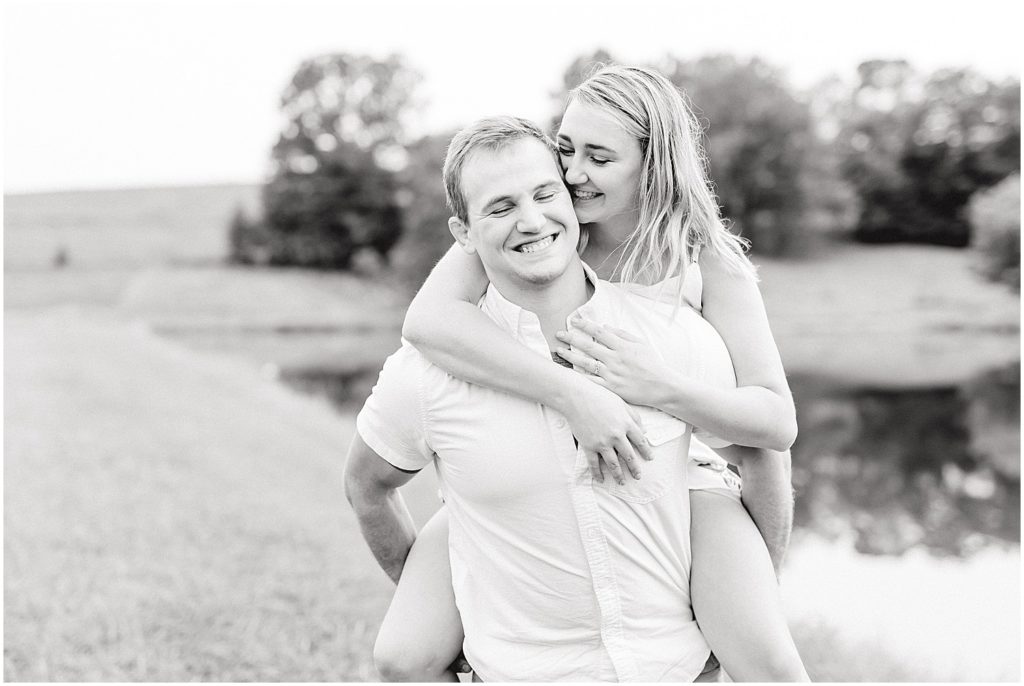 black and white image of couple giving piggy back ride on farm during missouri engagement session