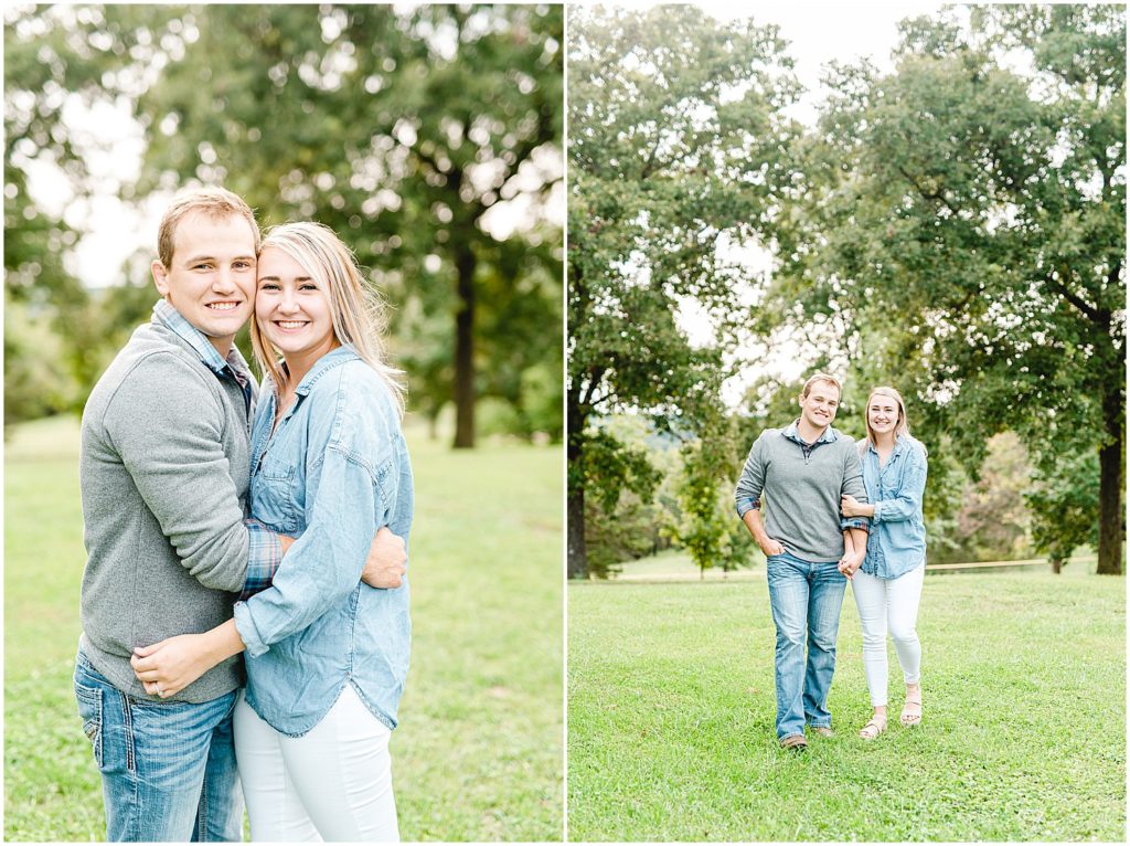 couple smiles and walks together under trees for engagement pictures