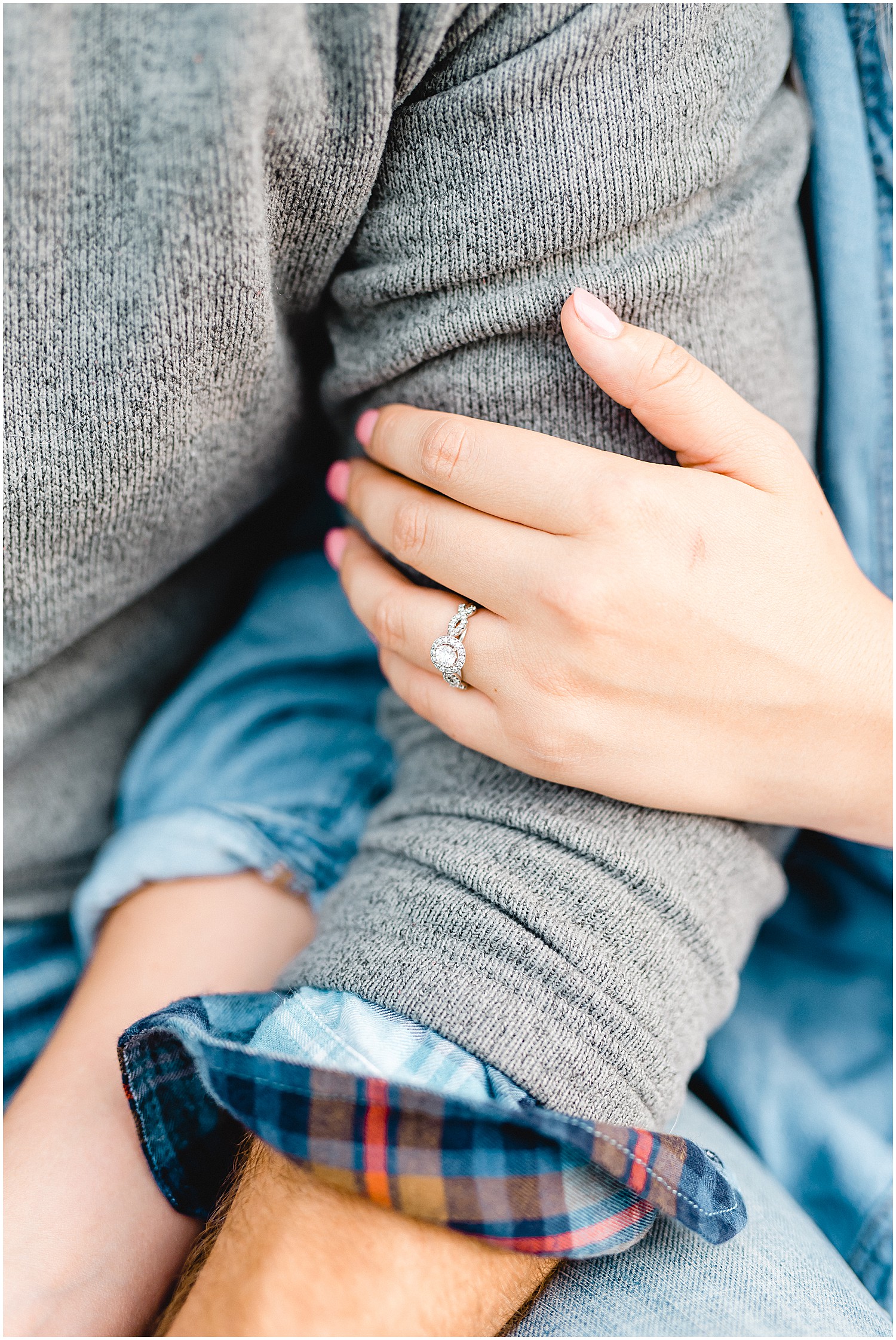 close up of engagement ring on woman's hand holding her fiancé's arm