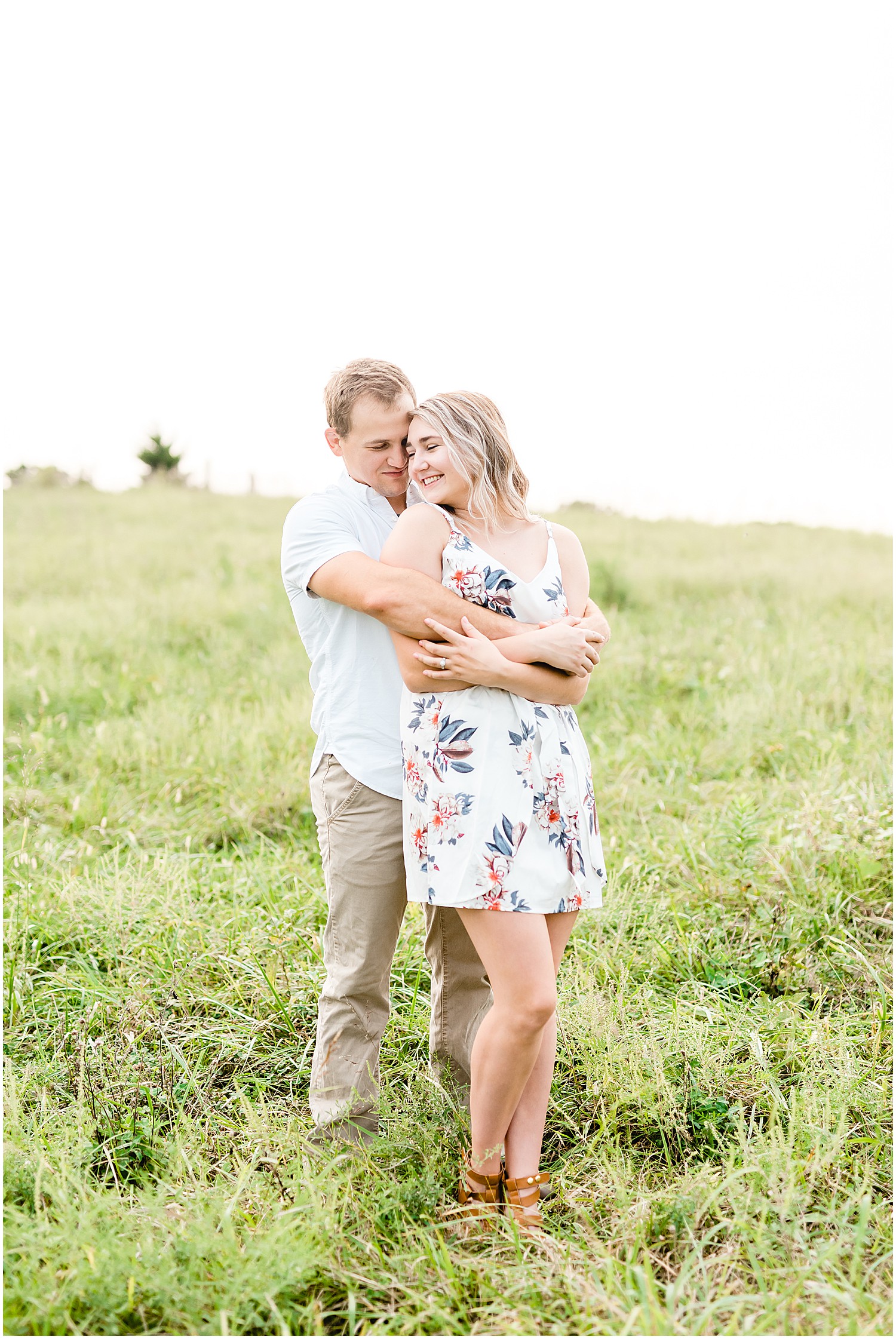 couple hugs on grassy field during missouri engagement session