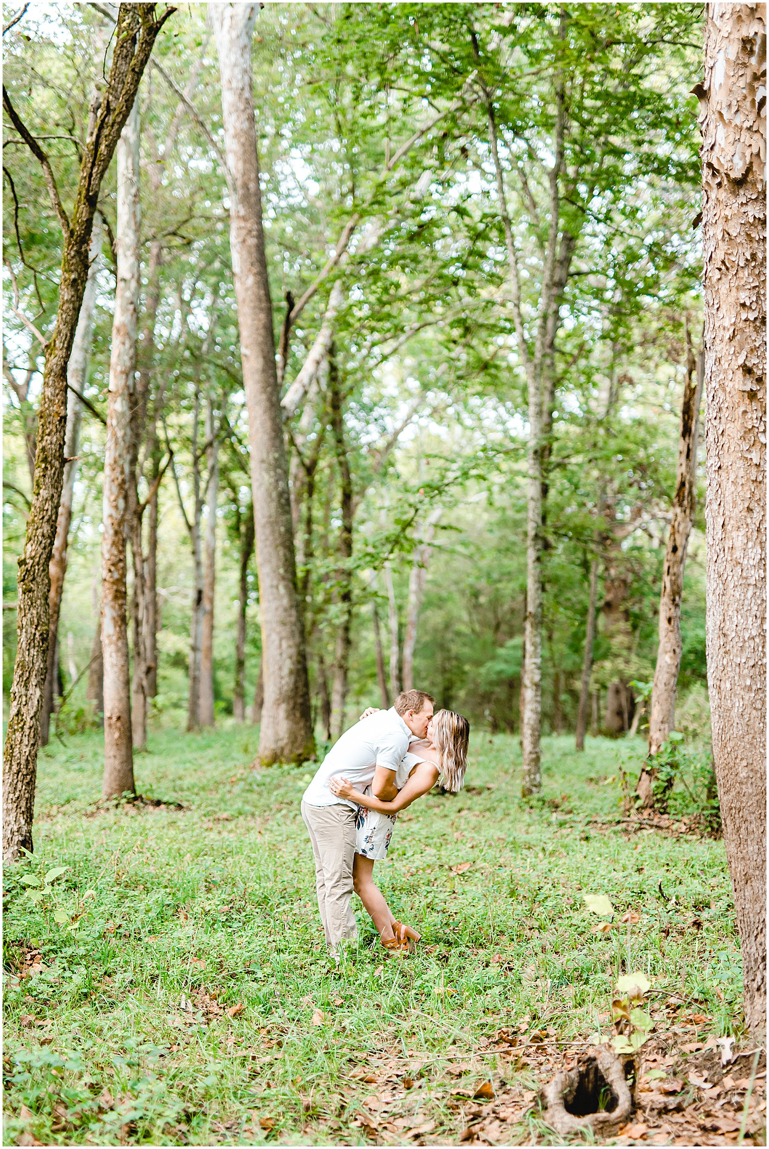 engaged couple kisses in a grove of trees for engagement pictures on farm in missouri