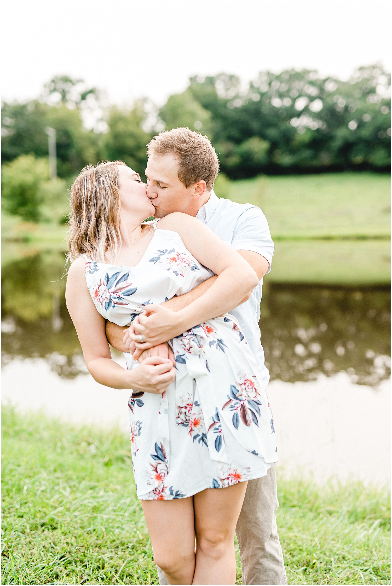 couple hugs and kisses next to lake during missouri farm engagement session