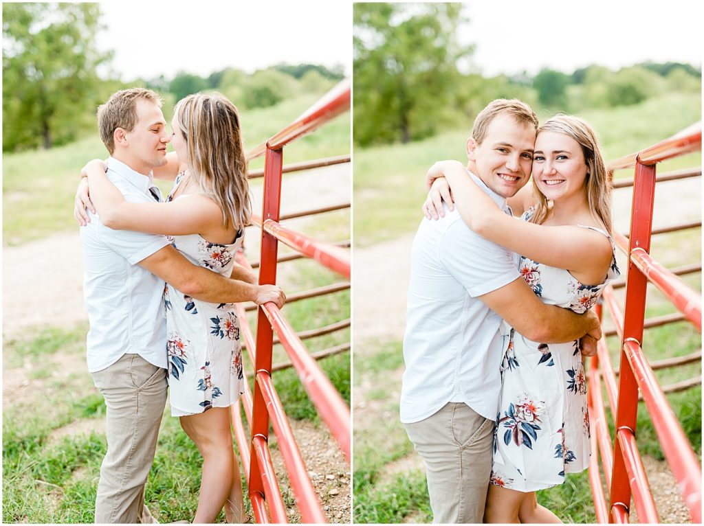 couple stands next to a red fence and kiss during engagement session on missouri farm