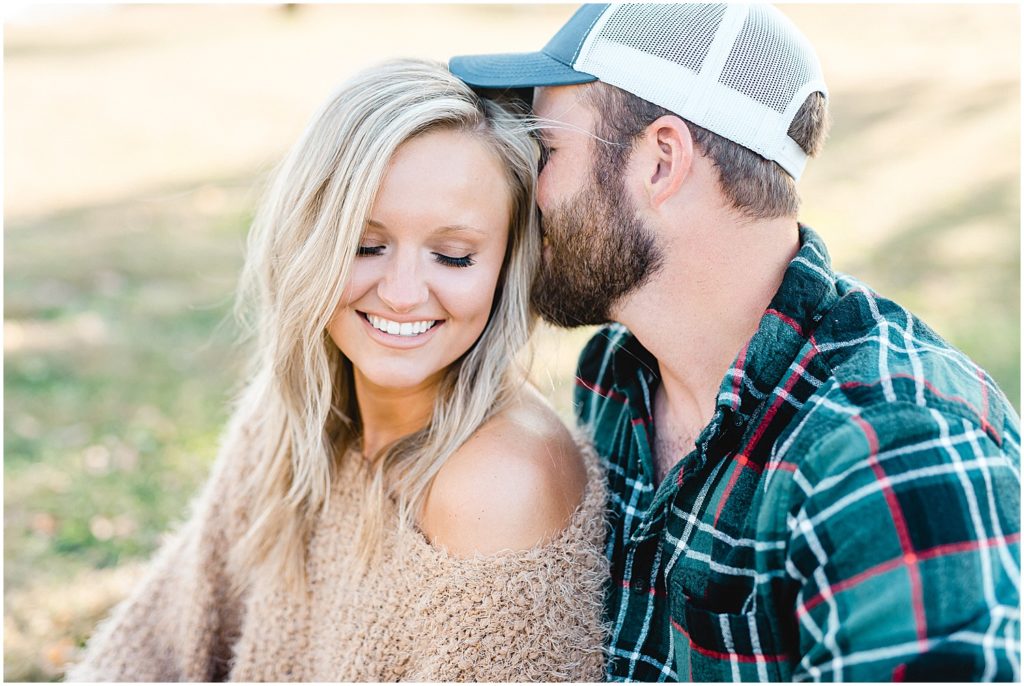 man kisses fiance while she smiles during engagement session